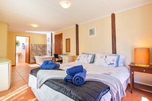 A hotel room with a bed, a desk, a chair, a bathroom, and a nightstand with a lamp.