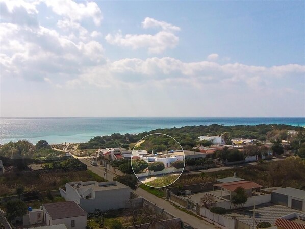 Un quartier résidentiel situé sur la côte, avec des maisons, un ciel dégagé et une vue sur la mer.