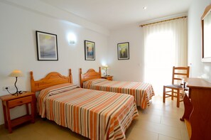 Een hotelkamer met twee bedden, een bureau, een stoel en een lamp.