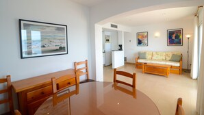 Una sala de estar moderna con una mesa de comedor, sillas, un sofá y obras de arte en las paredes.