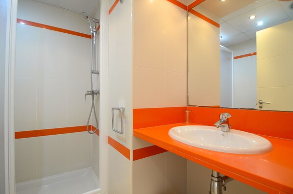 Een badkamer met een wit wastafel, een oranje aanrechtblad en een douche.