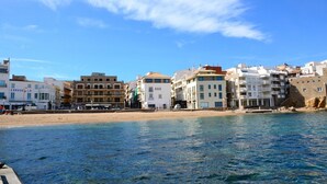 Une ville côtière avec des bâtiments qui bordent la plage, un ciel bleu dégagé et une mer calme.
