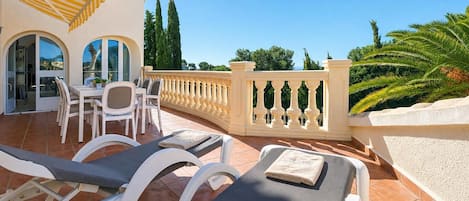 A terrace with lounge chairs, a dining area, and a view of the sea.