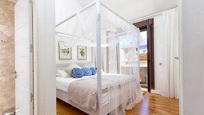 A bedroom with a canopy bed, a wooden floor, and a view of the outside. - Kim - Holiday Penthouse Malaga City (Málaga)