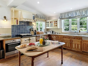 A kitchen with a wooden table, a stove, and a window with curtains.