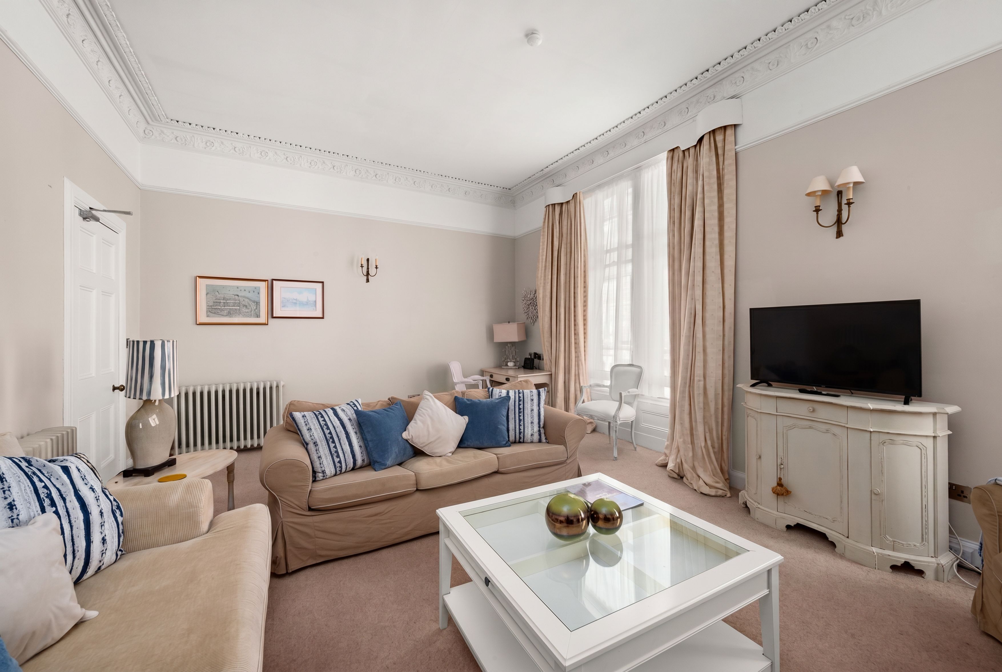 A living room with a sofa, a coffee table, a television, and a cabinet.