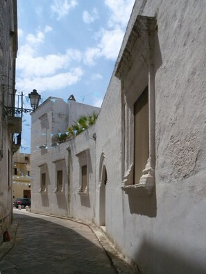 Una calle estrecha con edificios blancos, un camino pavimentado y cielo despejado.