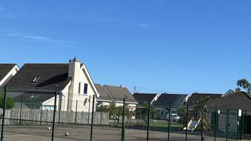 A residential area with houses, a fenced tennis court, and a clear blue sky.