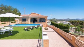 Une maison avec une piscine, un patio couvert et une vue sur le paysage environnant.