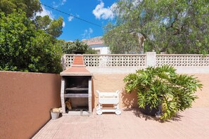 A barbecue area with a grill, a cart, and a potted plant. - Villa Andres - Plus (Calpe)