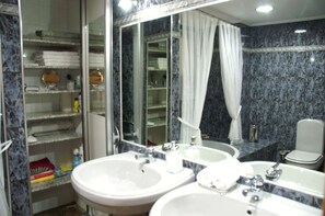 A bathroom with two sinks, a toilet, and a glass-enclosed shower area.