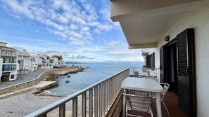Un balcon donnant sur la mer, un mur de pierre et des bâtiments en arrière-plan.