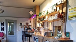 Uma cozinha rústica com prateleiras de madeira, um espaço de bar e uma área de jantar com cadeiras.