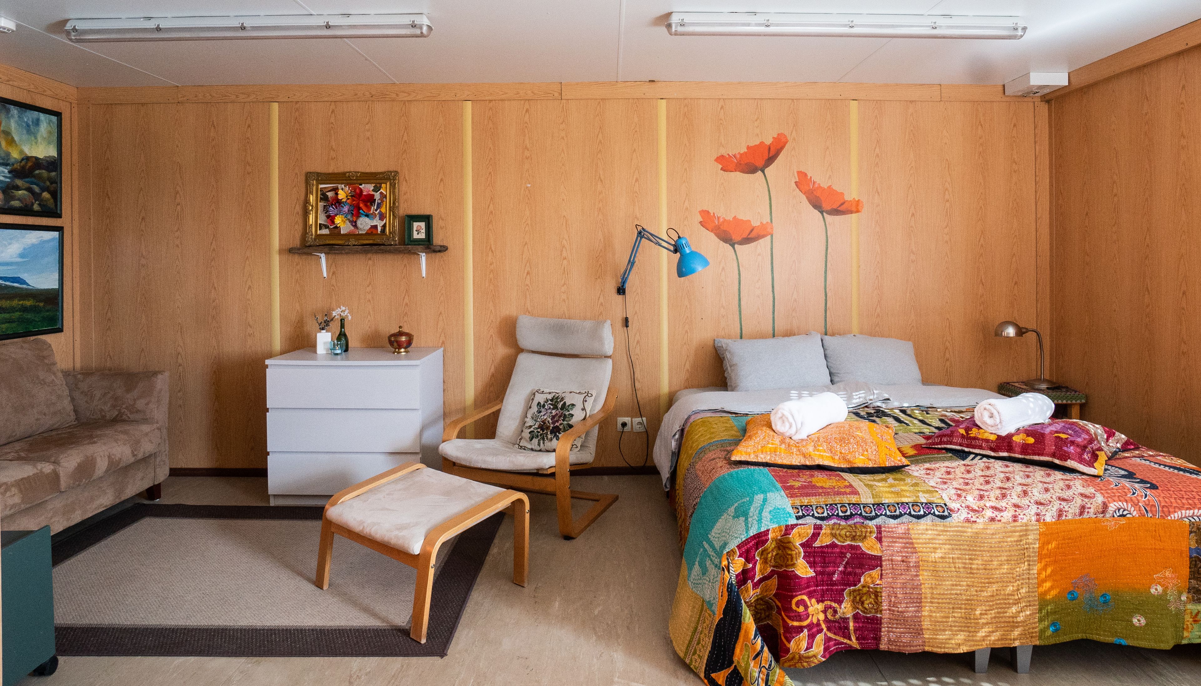 A bedroom with a bed, a chair, a desk, and a dresser.