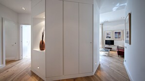 Ein modernes Interieur mit Holzboden, einem weißen Kleiderschrank und einer Wohnbereich mit Fernseher und gerahmten Bildern.