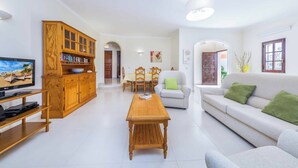 Un salon comprenant un meuble en bois, un téléviseur, un canapé et un coin repas.