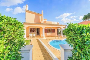A large house with a swimming pool, surrounded by lush greenery.
