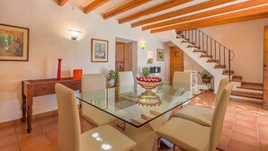 A dining area with a glass table, wooden chairs, and a staircase in the background. - Charming villa - 4km to beach and 2km to Old Town! (Palma de Mallorca)