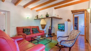 A living room with a red sofa, a patterned rocking chair, a coffee table, and a television. - Charming villa - 4km to beach and 2km to Old Town! (Palma de Mallorca)