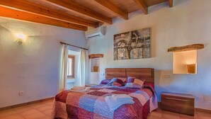 A bedroom with a large bed, wooden beams, a painting, and a nightstand. - Charming villa - 4km to beach and 2km to Old Town! (Palma de Mallorca)