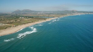 An aerial view of a coastal area with a beach, ocean, and distant mountains. - BEGUR-SA PUNTA-CALA MORETA (Begur)