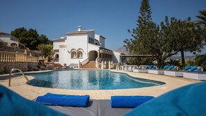 A pool area with lounge chairs and a staircase leading to a building.