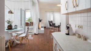 Une cuisine moderne avec des meubles blancs, une machine à café et un coin repas comprenant une table et des chaises en verre.
