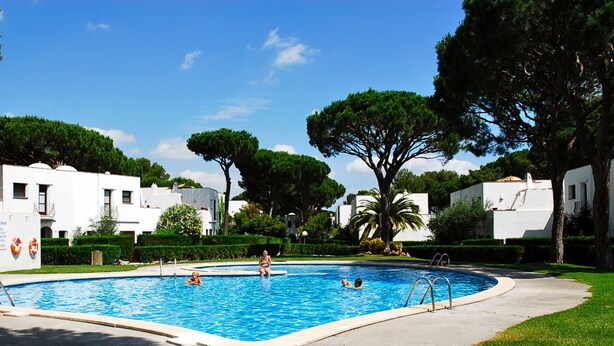 A swimming pool surrounded by white buildings, with trees and a clear sky. - PIVERD DEL GOLF 56 (Pals)
