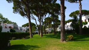 A courtyard with trees, white buildings, and a well-maintained lawn. - PIVERD DEL GOLF 56 (Pals)