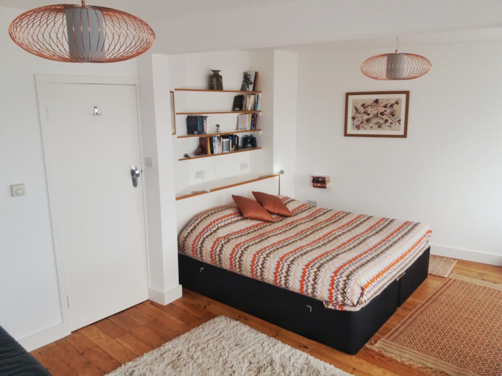 Une chambre à coucher avec un lit, une bibliothèque, une porte et un luminaire suspendu.