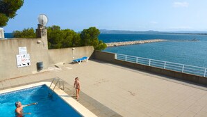 A swimming pool with a view of the sea, a satellite dish, and a sign with symbols.