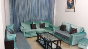Ein Wohnzimmer mit zwei Sofas, einem Couchtisch und einem gestreiften Vorhang.