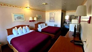 A hotel room with two beds, a desk, and a kitchenette. - Western Inn (Green River)