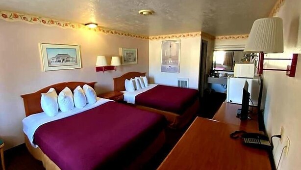 A hotel room with two beds, a desk, and a kitchenette. - Western Inn (Green River)