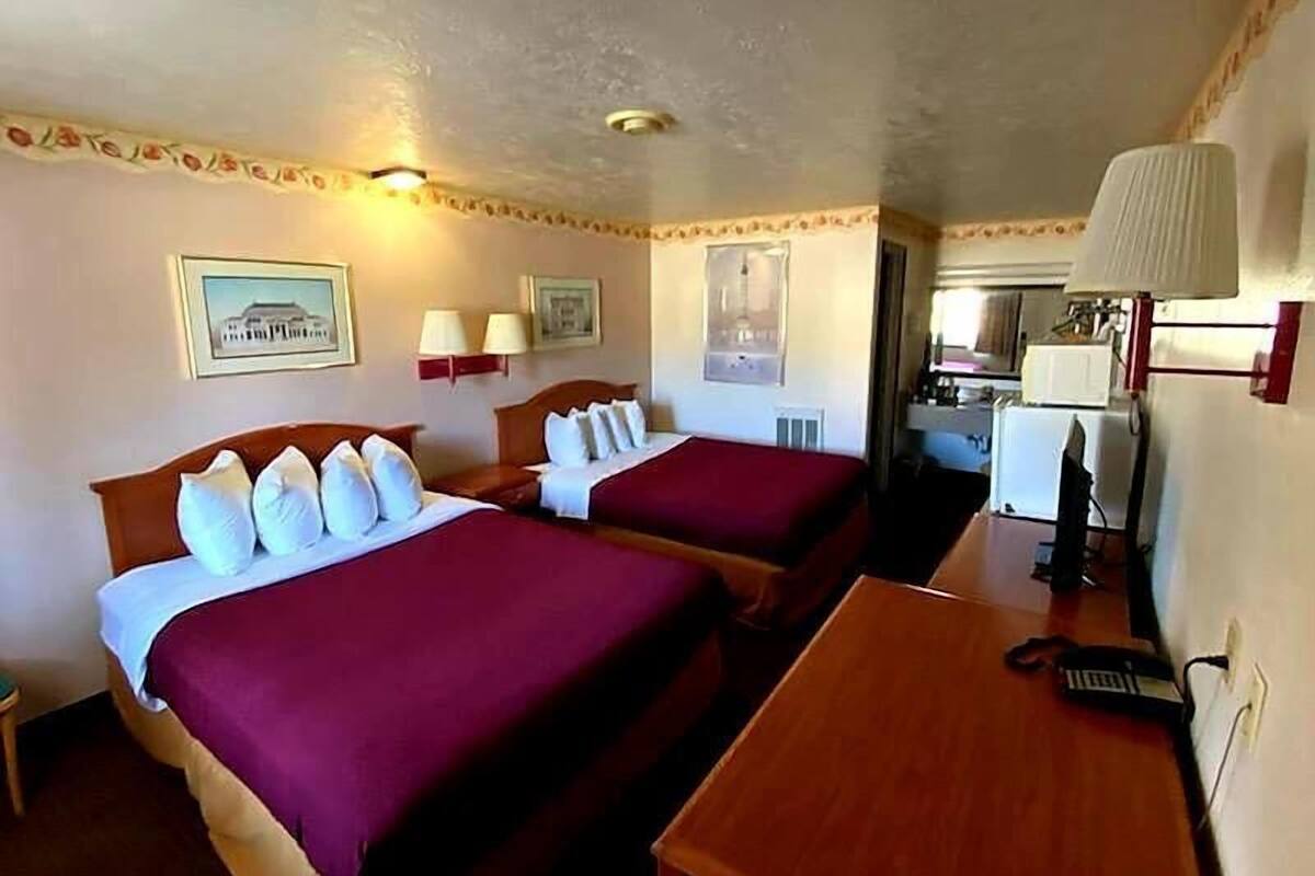 Habitación de hotel con dos camas, un escritorio y una kitchenette.