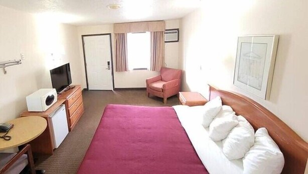 A hotel room with a bed, a desk with a computer, a chair, and a television. - Western Inn (Green River)