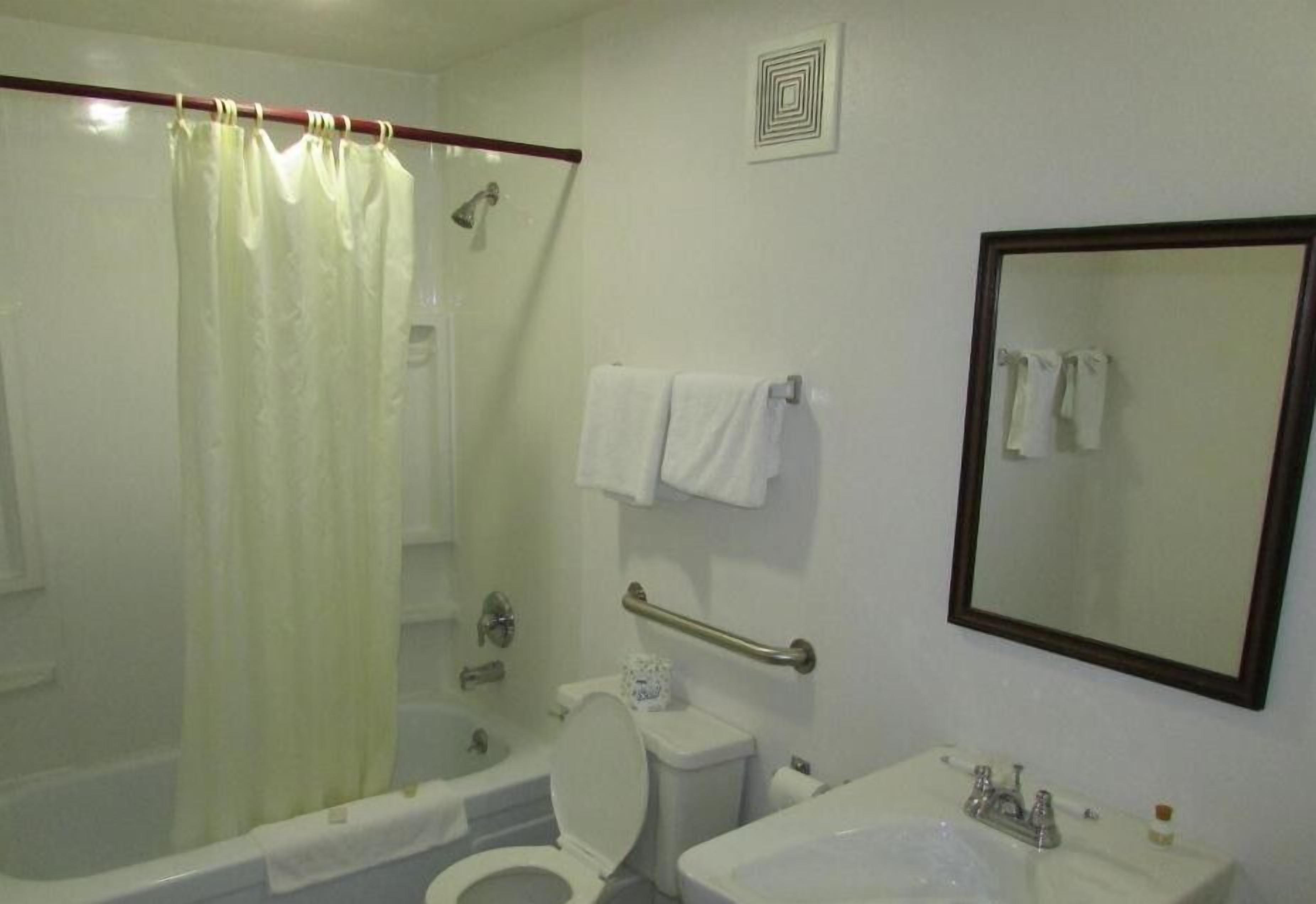 A bathroom with a bathtub, toilet, sink, and a mirror.