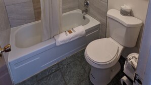 A modern bathroom with a bathtub, shower, toilet, and a towel rack. - Western Inn (Green River)