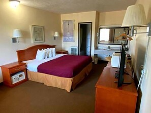 Relax in this inviting room with a large bed, wooden nightstand, and desk.