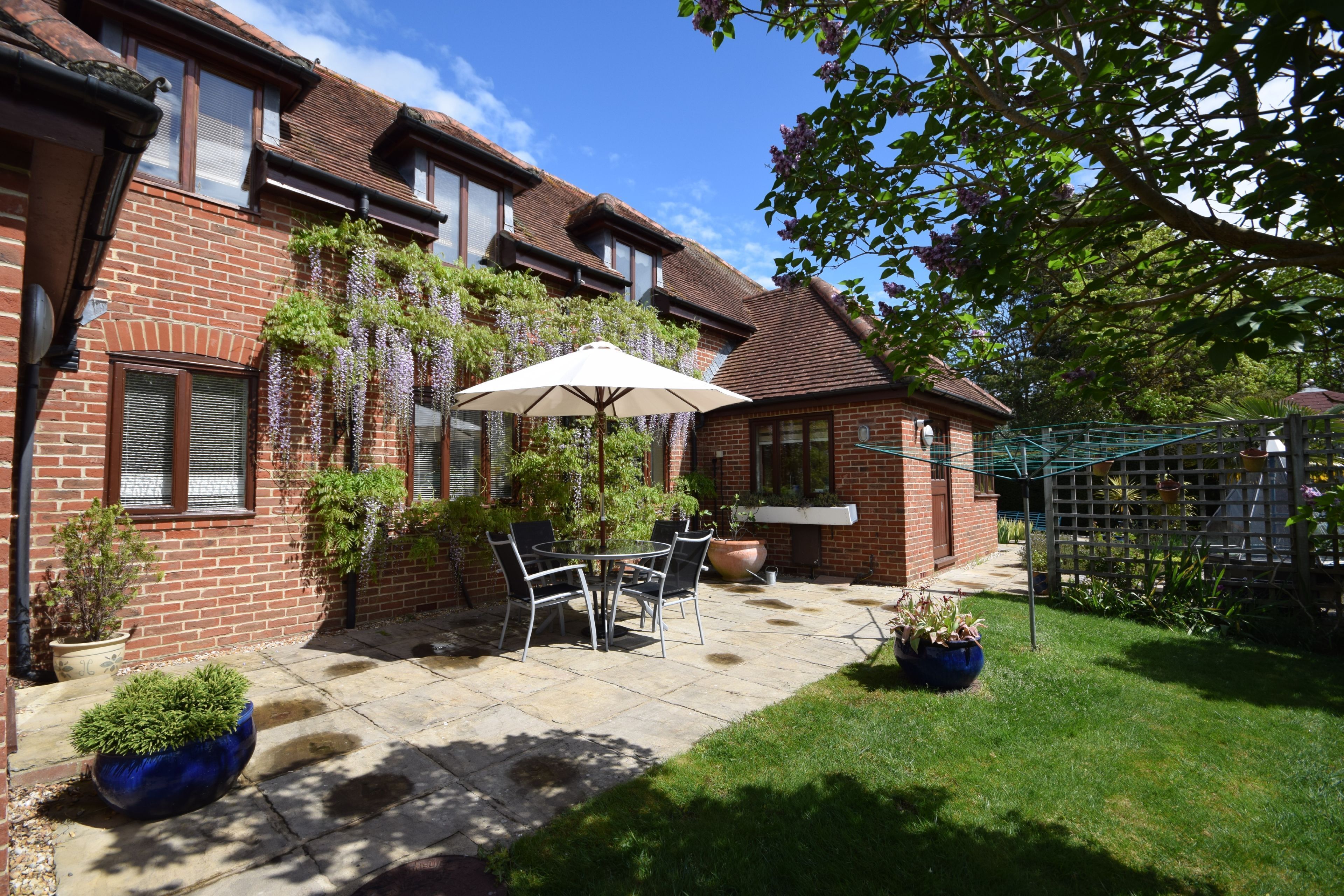 A brick house with a patio, a table with chairs, and potted plants.
