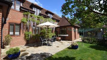 A brick house with a patio, a table with chairs, and potted plants.