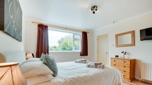A bedroom with a bed, bedside lamps, a dresser, a mirror, and a window with curtains. - 4 Bed in Appledore (oc-tidal) (Appledore)