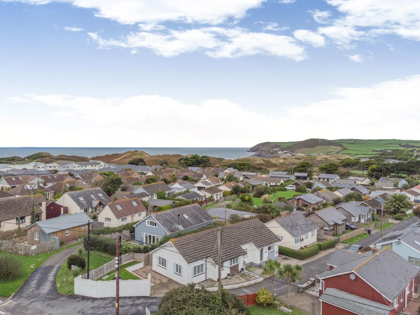 Un quartier résidentiel situé sur la côte, avec des maisons, une route sinueuse et une vue sur la mer.