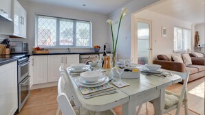 A modern kitchen with white cabinets, a dining table set for four, and a living area with a sofa and a coffee table.