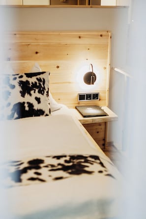 Une chambre à coucher avec une tête de lit en bois, une table de chevet avec une lampe et un lit agrémenté d’un coussin à motifs.