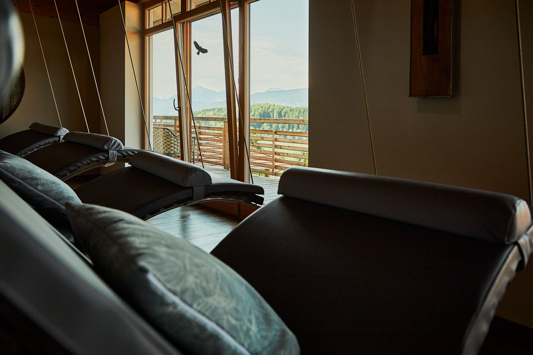 A massage chair in a room with a large window overlooking a balcony with a view of trees and mountains.
