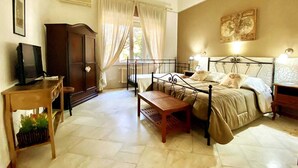 Een slaapkamer met een bed, nachtkastjes, een houten bankje, een kledingkast en een televisie op een voetstuk.