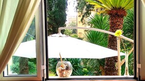 Een raam met uitzicht op een palmboom en een decoratieve parasol.