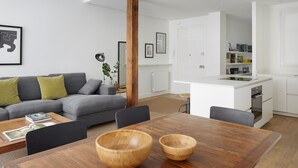 A modern living room with a wooden dining table, grey sofa, and a kitchen area in the background. - Miramon by FeelFree Rentals (San Sebastián)