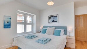 A bedroom with a large bed, a window, a framed picture, and a door. - 1 Bed in Woolacombe (oc-seablu) (Woolacombe)